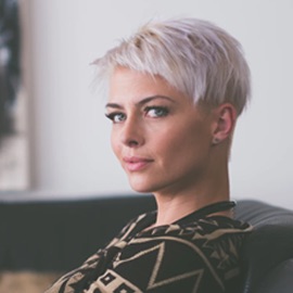 Woman with short white hair wearing patterned shirt